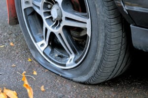 Flat tire of a car on the pavement. Side view close up
